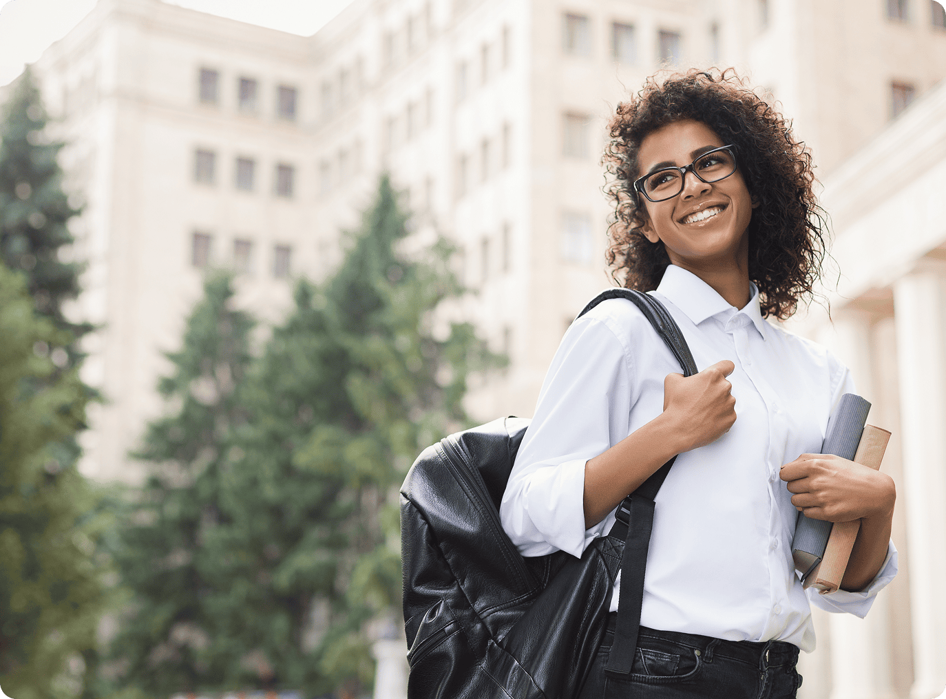 Smiling woman holding books on campus